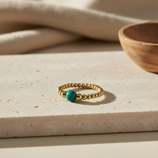 Bague flexible en or avec une bille turquoise et des billes dorées, style minimaliste, fabrication artisanale LeJu.