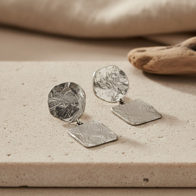 Boucles d'oreilles pendantes argentées horizons boutique, composées d'un disque texturé et d'un carré lisse, fermoir poussette.