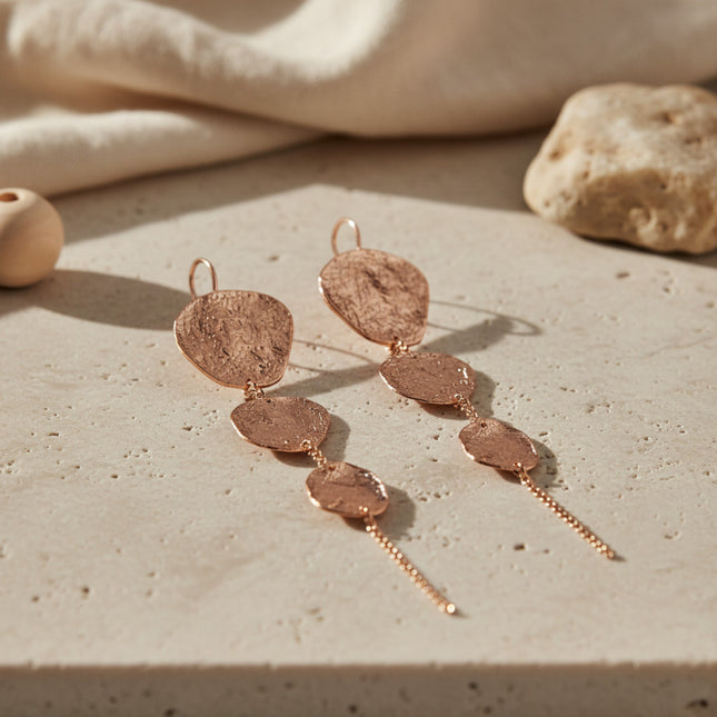 Boucles d'oreilles longues dorées à l'or rose de Horizons Boutique, ornées de trois écus ronds texturés en cascade. Fabrication artisanale grecque.