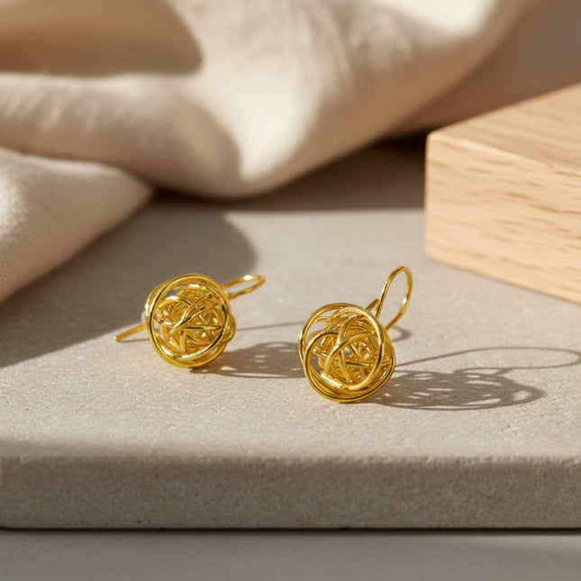 Boucles d'oreilles dorées en forme de sphère torsadée, fermoir à crochet, fabrication artisanale par Horizons Boutique.