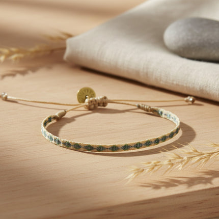 Bracelet tissé main Guanabana tons bleus et verts, cordon ajustable, breloque ronde dorée, style ethnique chic.