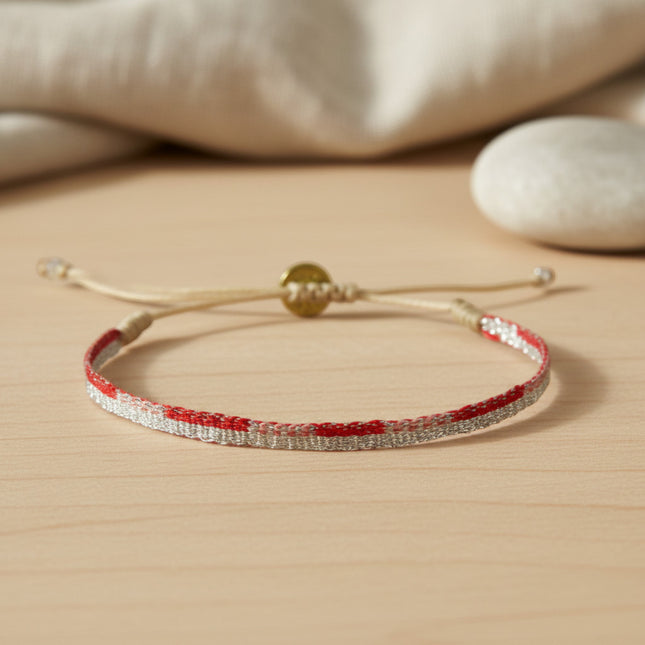 Bracelet tissé main Guanabana en fils rouges et argentés, cordon beige ajustable, fermoir rond doré. Style ethnique chic.