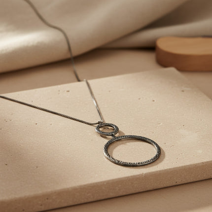 Horizons Boutique long collier Constellation en argent avec deux anneaux superposés.