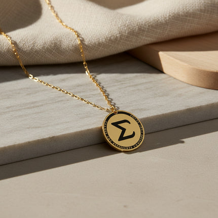 Collier horizons boutique en laiton plaqué or, médaille ronde gravée de la lettre Sigma et d'une inscription.